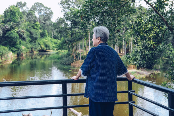 istock old senior woman looking at lake pond view 1183845733