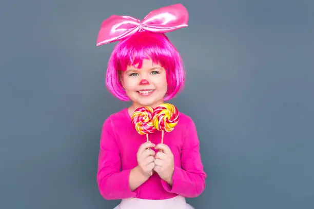Photo of Girl clown holds two candies and toothy smiling