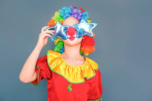 Photo of Funny girl in a clown suit and stupid eyeglasses air kissing