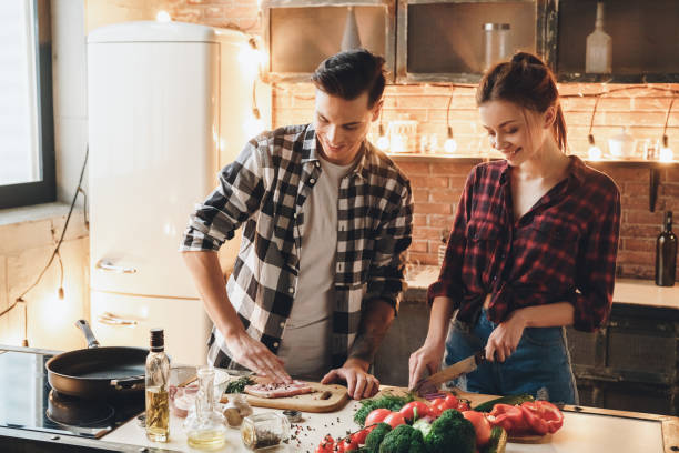 Couple preparing to receive guests cooking meat and salt stock photo