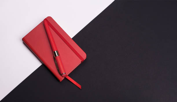 istock red Notepad with pen on white and black background. Top view. 1183846194