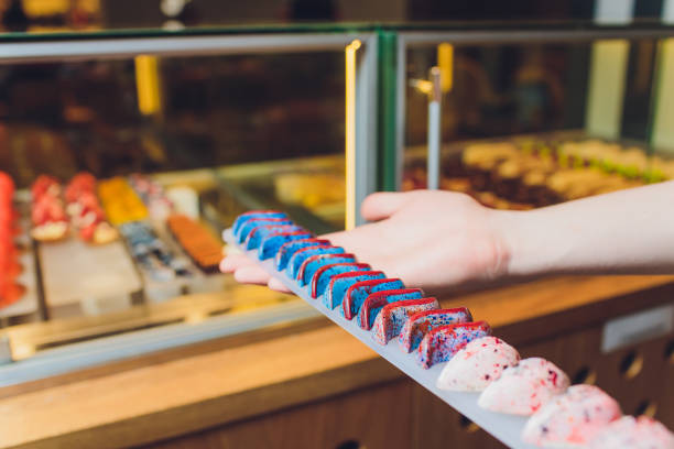 istock Close up of vendor's hands taking out cake from showcase in bakery. 1183846384