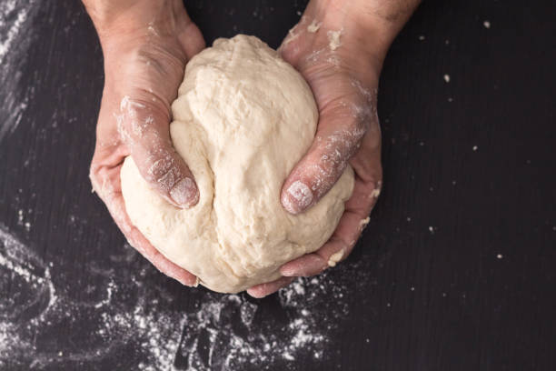 istock Male hands kneading dough, baking preparation closeup. 1183846492