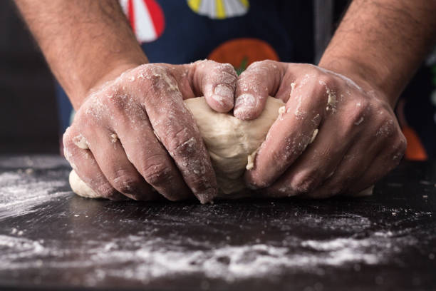 istock Male hands kneading dough, baking preparation closeup. 1183846510