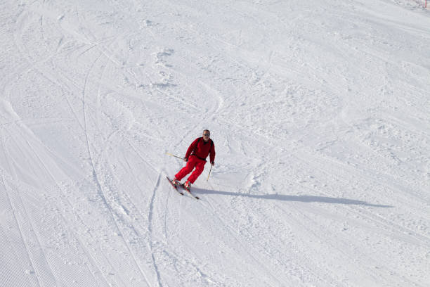 Skier on snowy sunlit ski slope at sun winter day