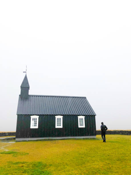 istock Búðir, Iceland: Man at Black Church (Búðakirkja) in Rain 1183850112