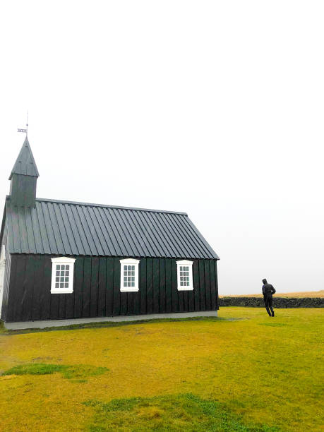 istock Búðir, Iceland: Man at Black Church (Búðakirkja) in Rain 1183850139