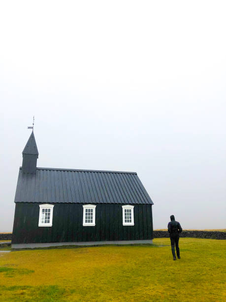 istock Búðir, Iceland: Man at Black Church (Búðakirkja) in Rain 1183850211