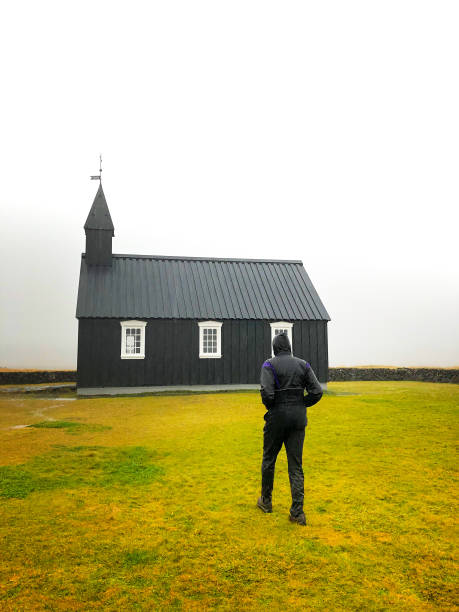 istock Búðir, Iceland: Man at Black Church (Búðakirkja) in Rain 1183850246