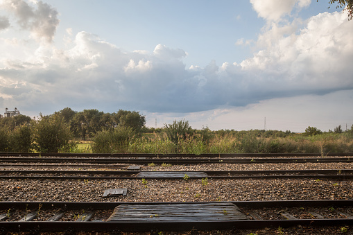 Picture of the train tracks in the station of Uljma, Serbia, taken during a warm summer dusk after a short rain, with railway tracks and platforms