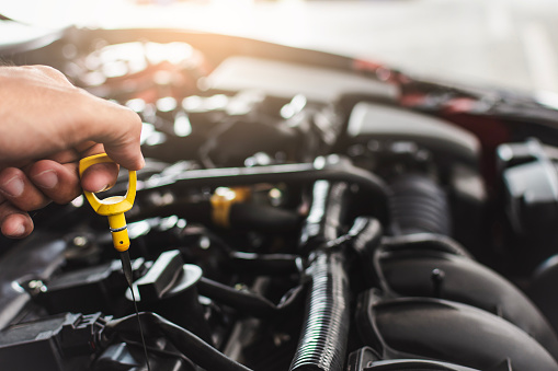 Man servicio mecánico mantenimiento de mantenimiento de mantenimiento coche de mantenimiento coche Compruebe el coche de nivel de aceite del motor en la sala de exposición del garaje concesionario borroso.