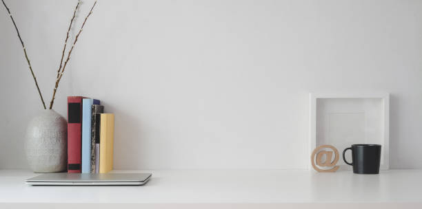 istock Minimal workspace with copy space, mock up frame and office supplies on white wooden table and white wall 1183864967