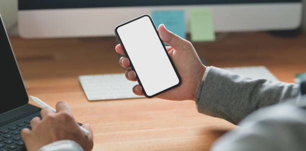 istock Cropped shot of young businessman holding blank screen smartphone while working on his project 1183864983