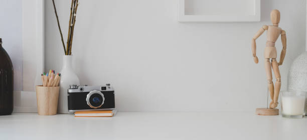istock Minimal workspace with copy space, camera and office supplies on white desk and white wall 1183865021