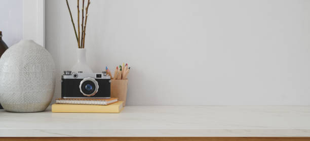 istock Minimal workspace with copy space, camera and office supplies on white desk and white wall 1183865047