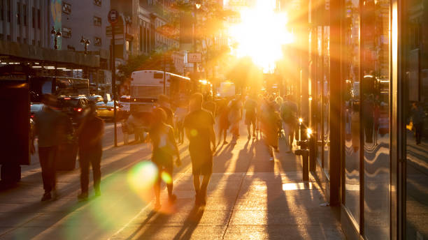 la lumière du soleil brille sur les foules diverses de personnes marchant en bas du trottoir occupé sur la 34ème rue à new york city - dusk people manhattan new york city photos et images de collection