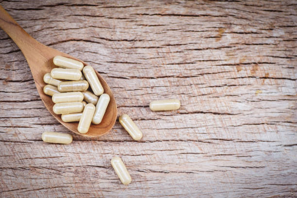 istock Herbal Medicines / Natural herb capsules on wooden spoon and rustic background selective focus 1183868943