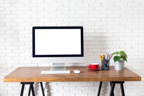 istock Mockup blank screen computer on a wooden desk. desktop empty white screen, with workspace and office supplies on table 1183870247