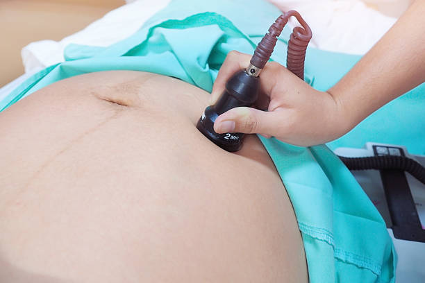 Close up shot photo of asian woman checking blood flow in placenta and uterus with Doppler fetal monitor during prenatal checkup by gynecologist before Caesarean section stock photo