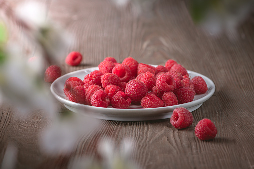 ripe raspberries on a plate on dark background