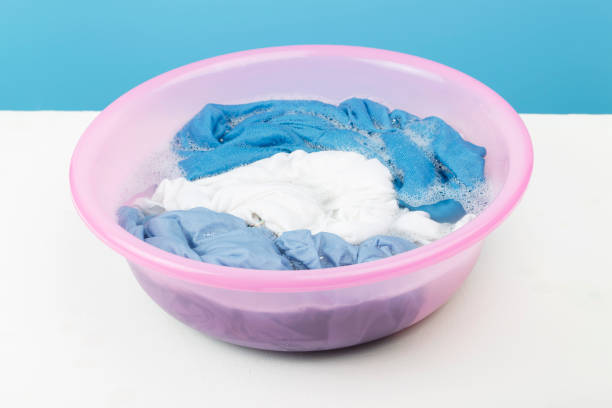 istock White and blue clothes washed with a basin with soap bubbles, close-up 1183886727