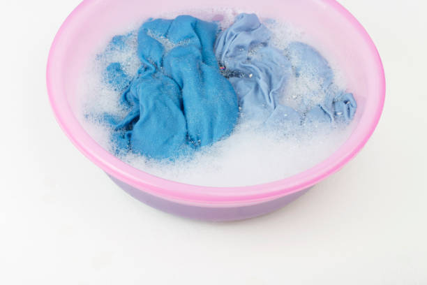 istock Blue clothes washed with basin with soap bubbles on white background, top view 1183886729