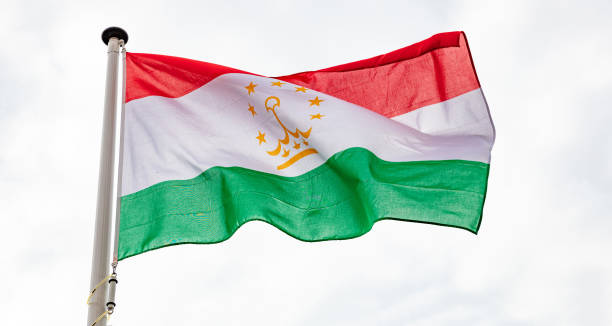 tajikistan flag waving against cloudy sky background - tajik flag imagens e fotografias de stock