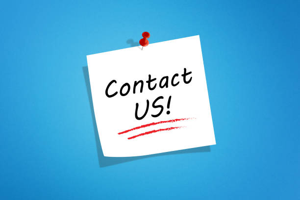 istock White post it note paper with contact us message on blue background 1183895333