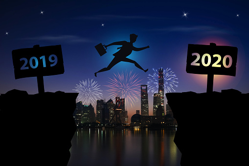 Businessman jumping between 2019 and 2020 years with night city background