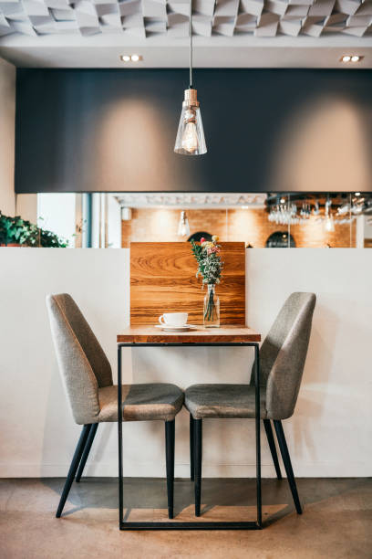 Table for two? Cropped shot of a coffee cup on a table and two chairs in an empty coffee shop during the day restaurants tables and chairs stock pictures, royalty-free photos & images
