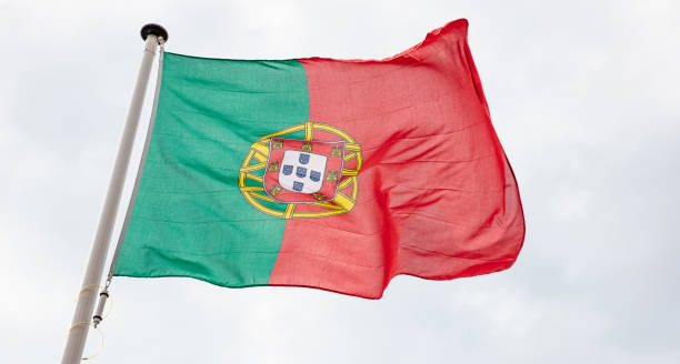istock Portuguese flag waving against cloudy sky background 1183896228