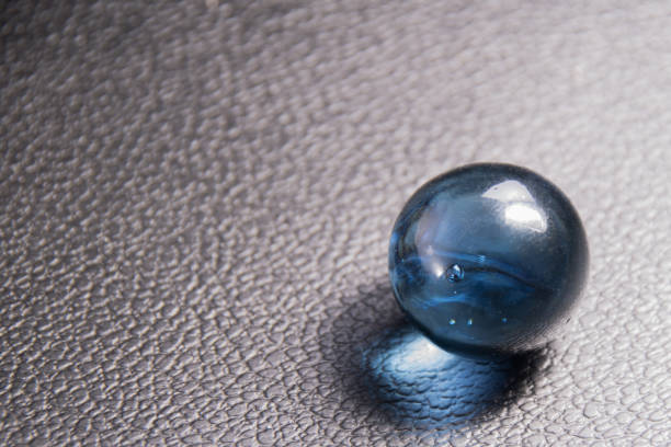 istock blue glass ball on black leather background 1183901245