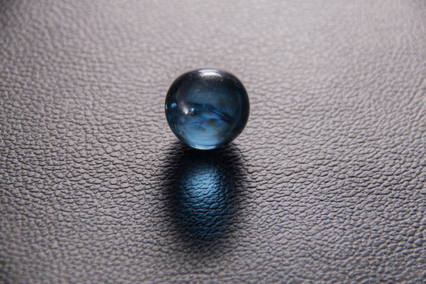 istock blue glass ball on black leather background 1183901251