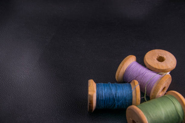 istock green blue purple white bobbins threads on black skin copyspace 1183901323