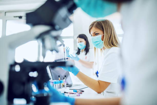 Small group of female laboratory assistants checking blood, using microscope and doing test for bacteria. Small group of female laboratory assistants checking blood, using microscope and doing test for bacteria. diagnostic medical tool stock pictures, royalty-free photos & images