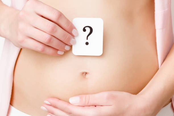 Woman showing question mark on naked belly. Gentle touch. Concept of baby planning, abdomen health or girls problems. Close up. Front view. Woman showing question mark on naked belly. Gentle touch. Concept of baby planning, abdomen health or girls problems. Close up. Front view. symptom stock pictures, royalty-free photos & images