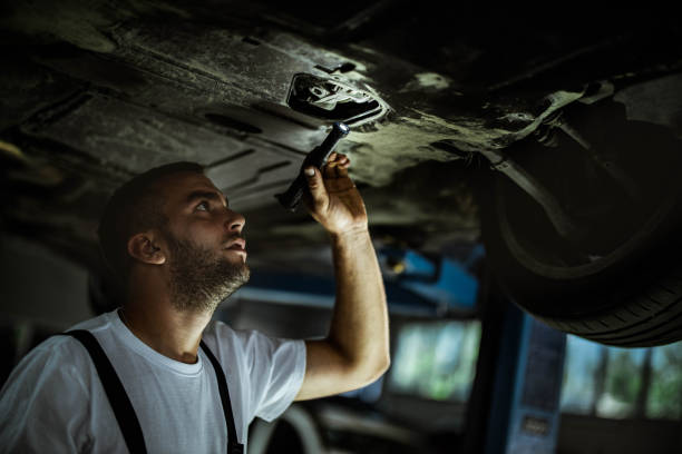 automechaniker arbeiten an chassis in einer werkstatt. - maintenance engineer car lamp protective workwear stock-fotos und bilder