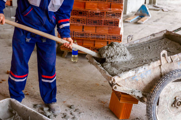 istock Worker is using shovel to unload wheelbarrow at building site 1183904661