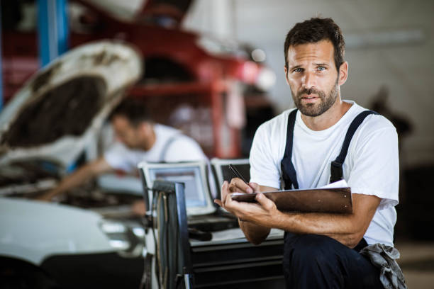 istock Young mechanic going through checklist in auto repair shop. 1183904769
