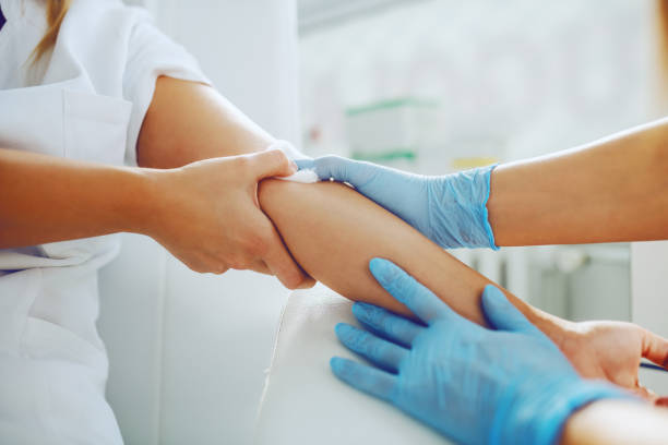 primer plano del asistente de laboratorio poniendo algodón absorbente en el brazo del paciente después de tomar muestras de sangre. - laboratory blood laboratory equipment medical sample fotografías e imágenes de stock