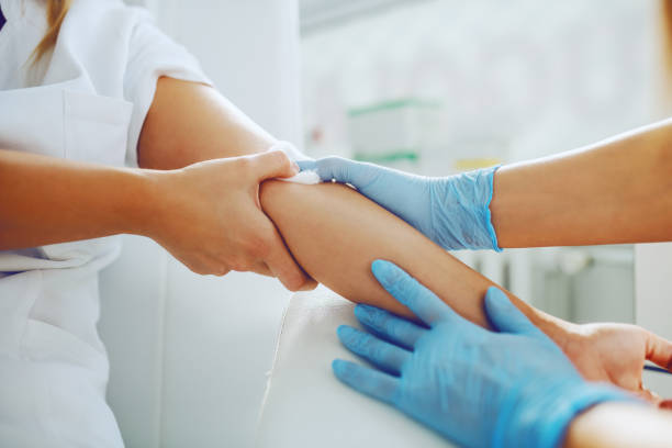 primo dell'assistente di laboratorio che mette cotone assorbente sul braccio del paziente dopo aver preso il campione di sangue. - aids test foto e immagini stock