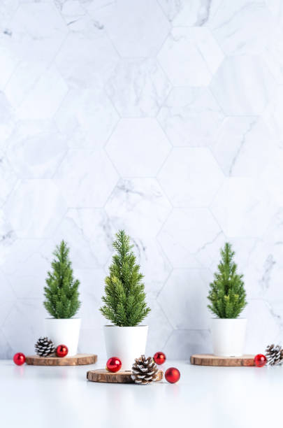 istock Three christmas tree with pine cone and decor xmas ball on white table and marble tile wall background.clean minimal simple style.holiday still life mockup banner with space to adding text 1183908148