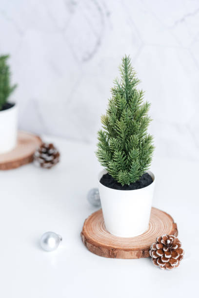 istock christmas tree with pine cone,decor xmas ball on wood log at white table and marble tile wall background.clean minimal simple style.holiday still life with space to adding text 1183908239
