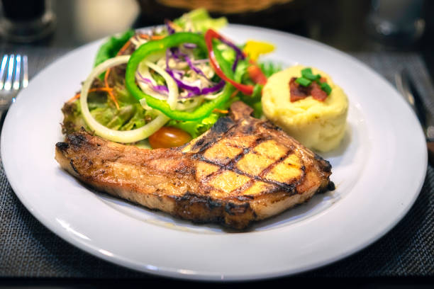 istock Grilled pork chops and vegetable salad. Steak on plate. 1183908543