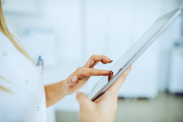 istock Close up of hardworking dedicated lab assistant using tablet for data entry of test results. 1183908582