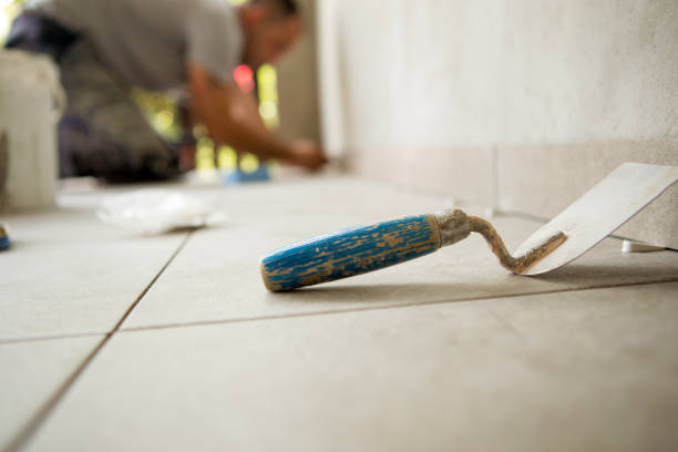 istock Trowel is on the floor and behind is a worker gluing ceramic tiles. 1183910444