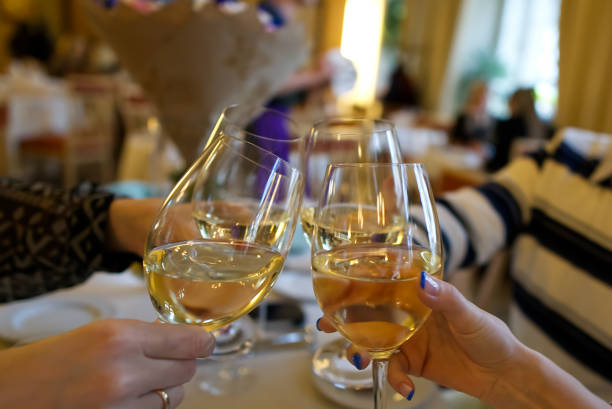Wine glasses with white wine in a restaurant. People clink glasses of wine in a restaurant celebrating a birthday. hands without people