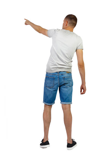 istock Back view of going handsome man in shorts pointing. 1183915442