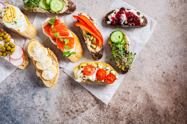 istock Open toasts with different toppings on gray-brown background, copy space, top view.  Flat lay of crostini with banana, pate, avocado, salmon, egg, cheese and berries. 1183917706