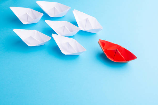 istock A red ship as a leader. White following it. Blue background 1183920153